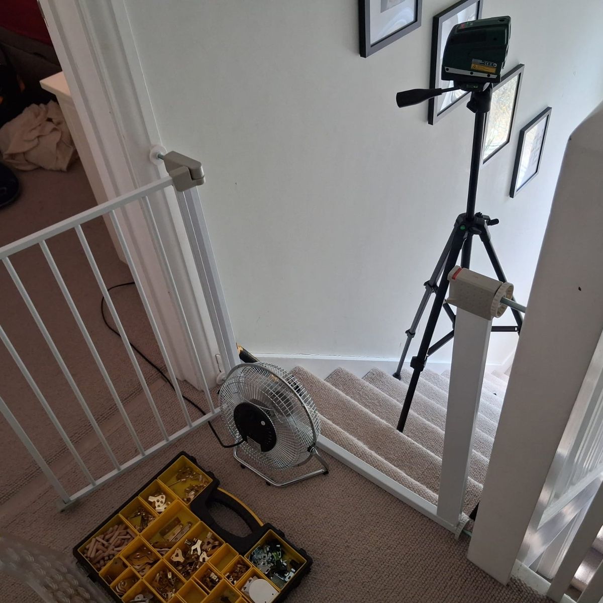Before: frames leaning on the stairs with a laser level set up on a tripod