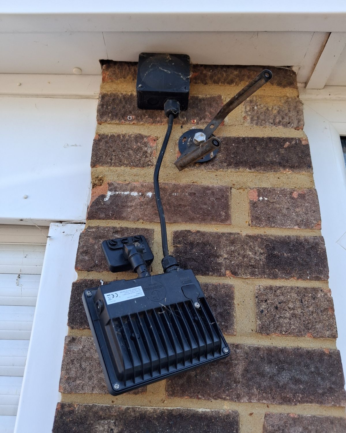 Before: an old floodlight hanging loose from a brick wall